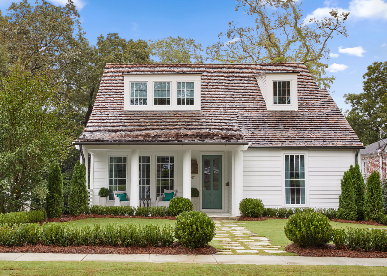 Front exterior elevation photo of a white cottage with teal door.