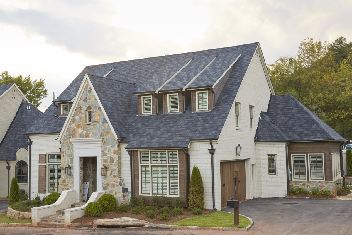 Front exterior elevation photo of cream colored home with warm wooden accents and large stone porch.