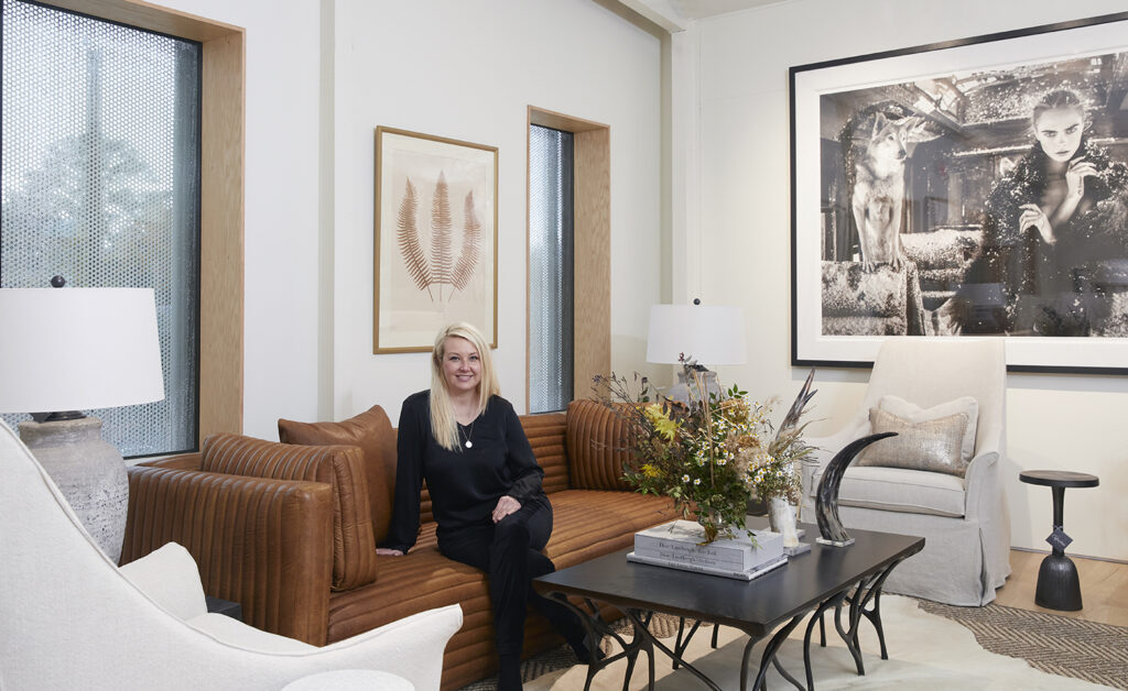 Leah sitting on a leather couch in a living room vignette.