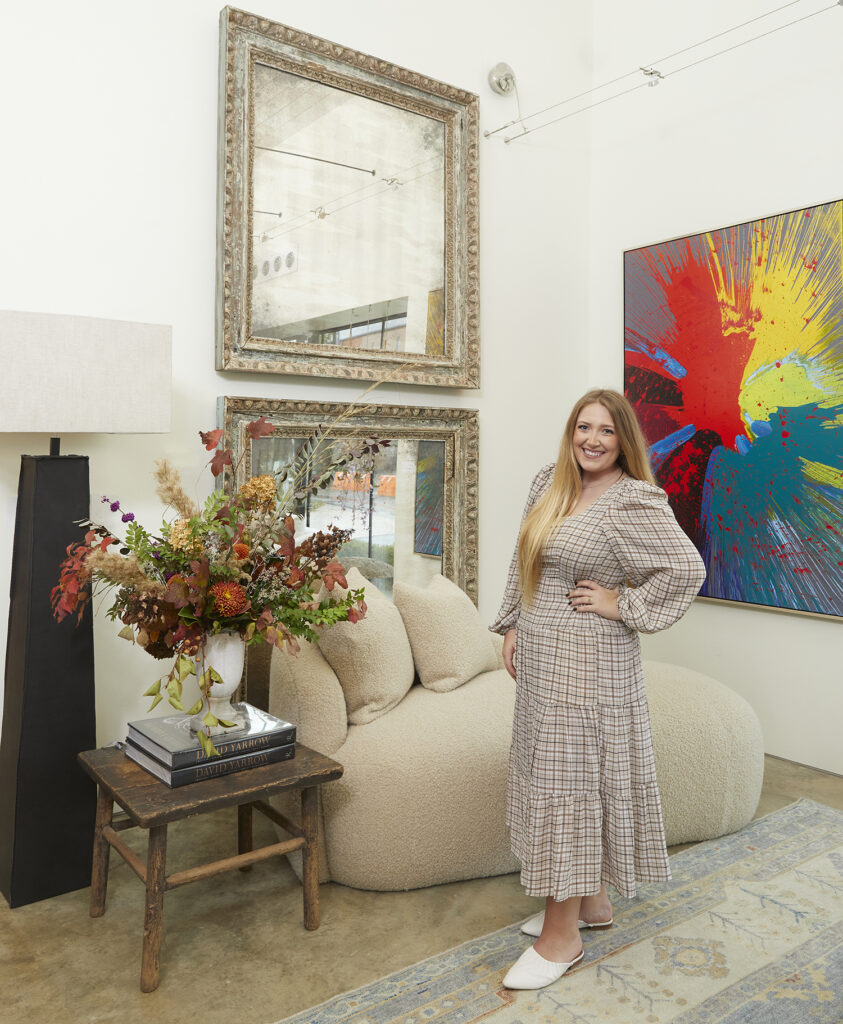 Audrey surrounded by elegant and rustic furniture pieces and art.