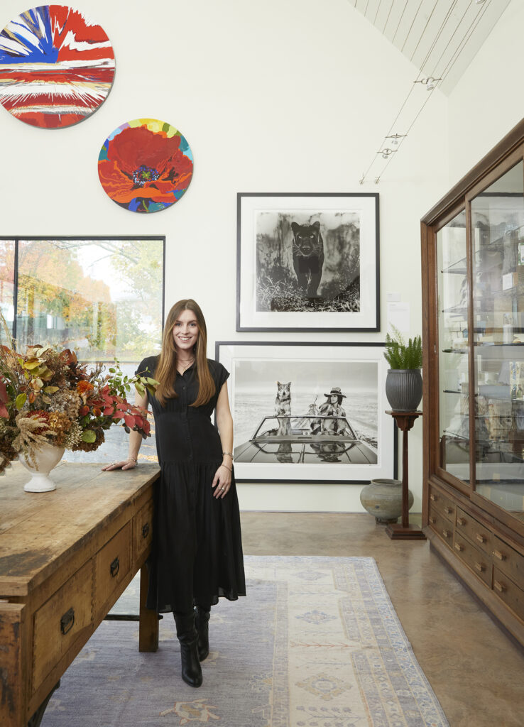 Isabelle standing in front of large photographs by David Yarrow and leaving on a large table.