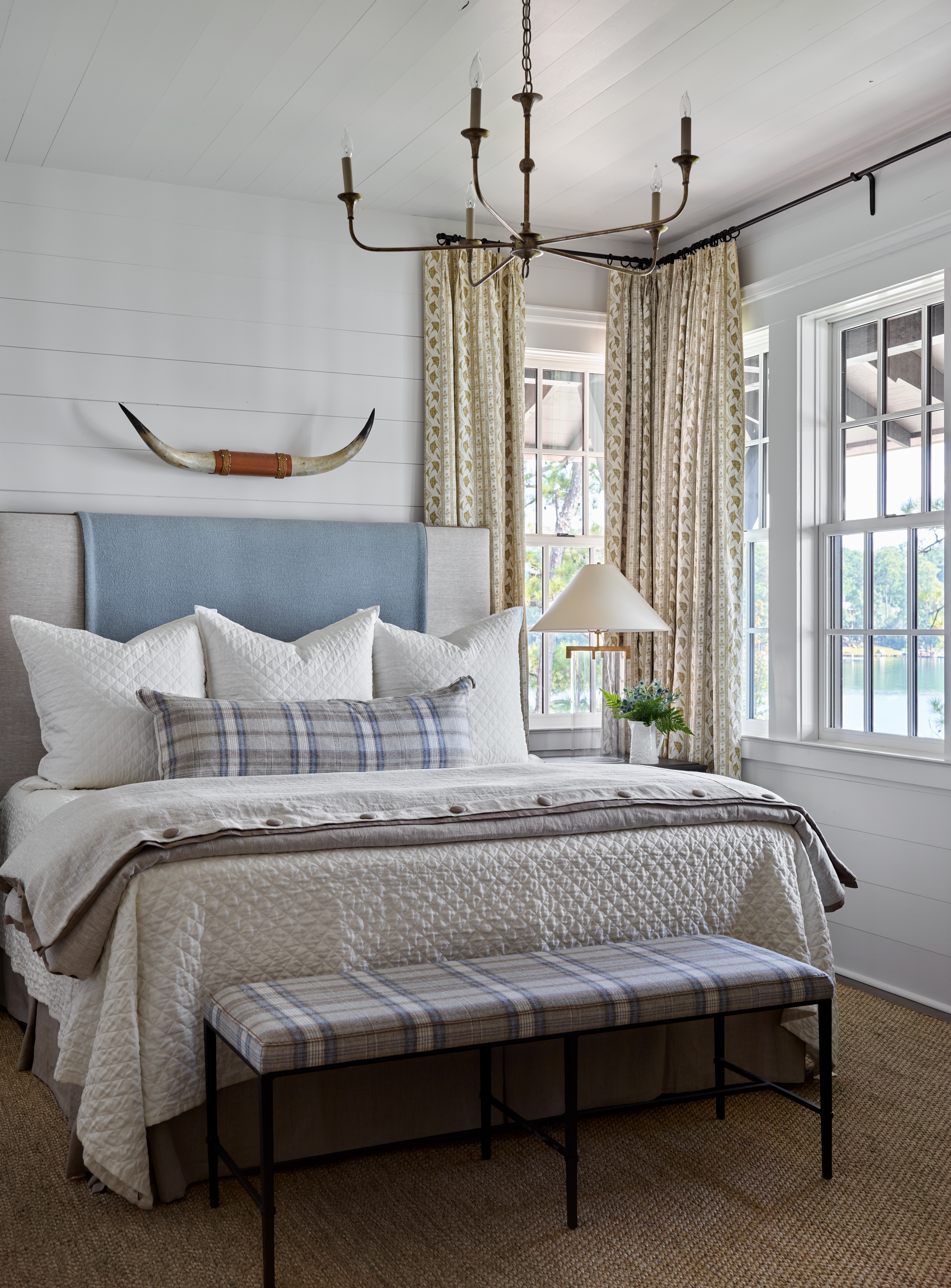 Bedroom with white wood walls overlooking lake.